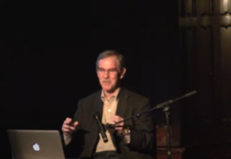 James Shapiro, in glasses, speaking at a lecture.