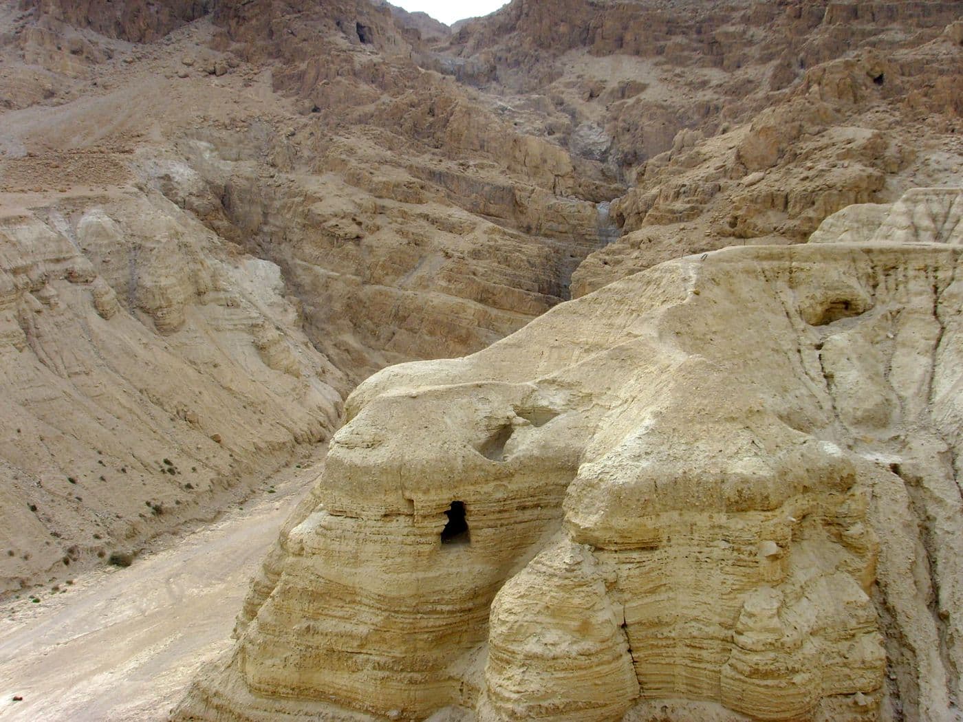 Pale desert cliffs with a dark cave opening.